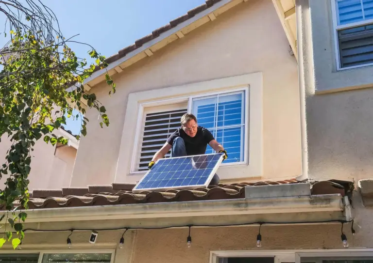 A guy installing solar panels on his own roof.
