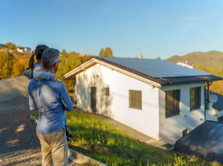 A man looking at his home with solar panels on the roof